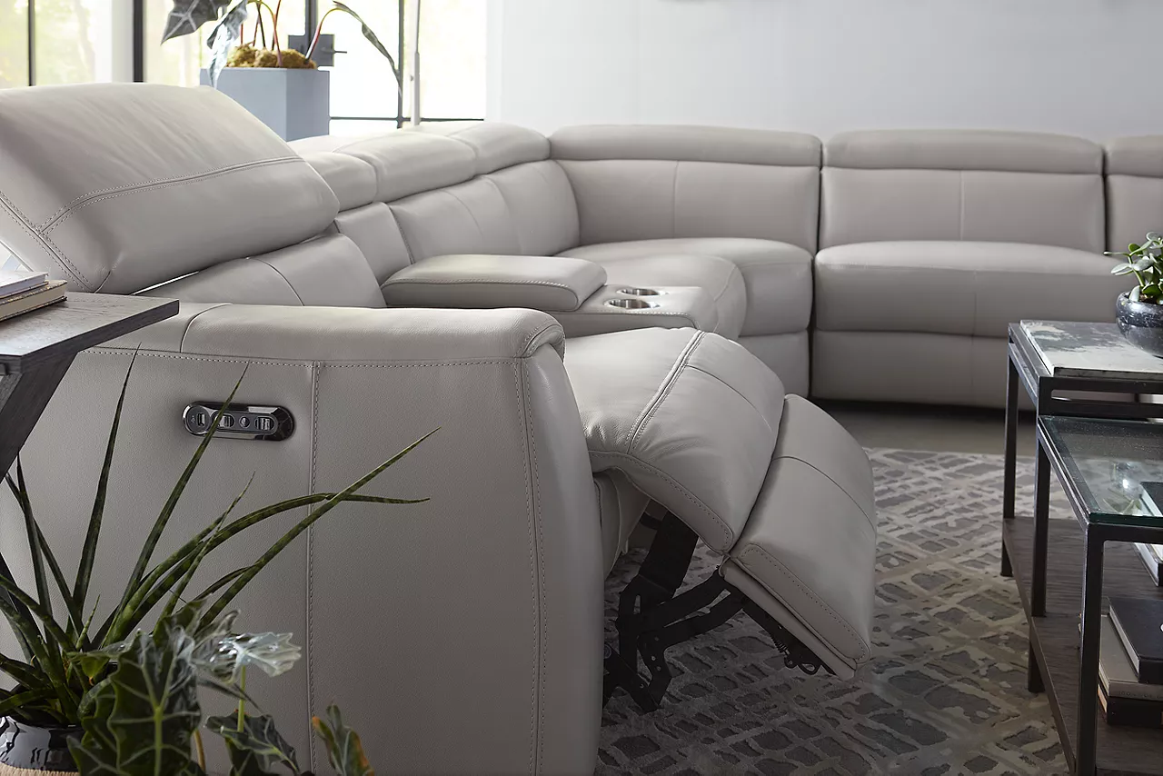 Leo Sectional in Dove Gray with on side reclined and the headrest pulled up and Keaton Bunching Coffee Table in a room scene.