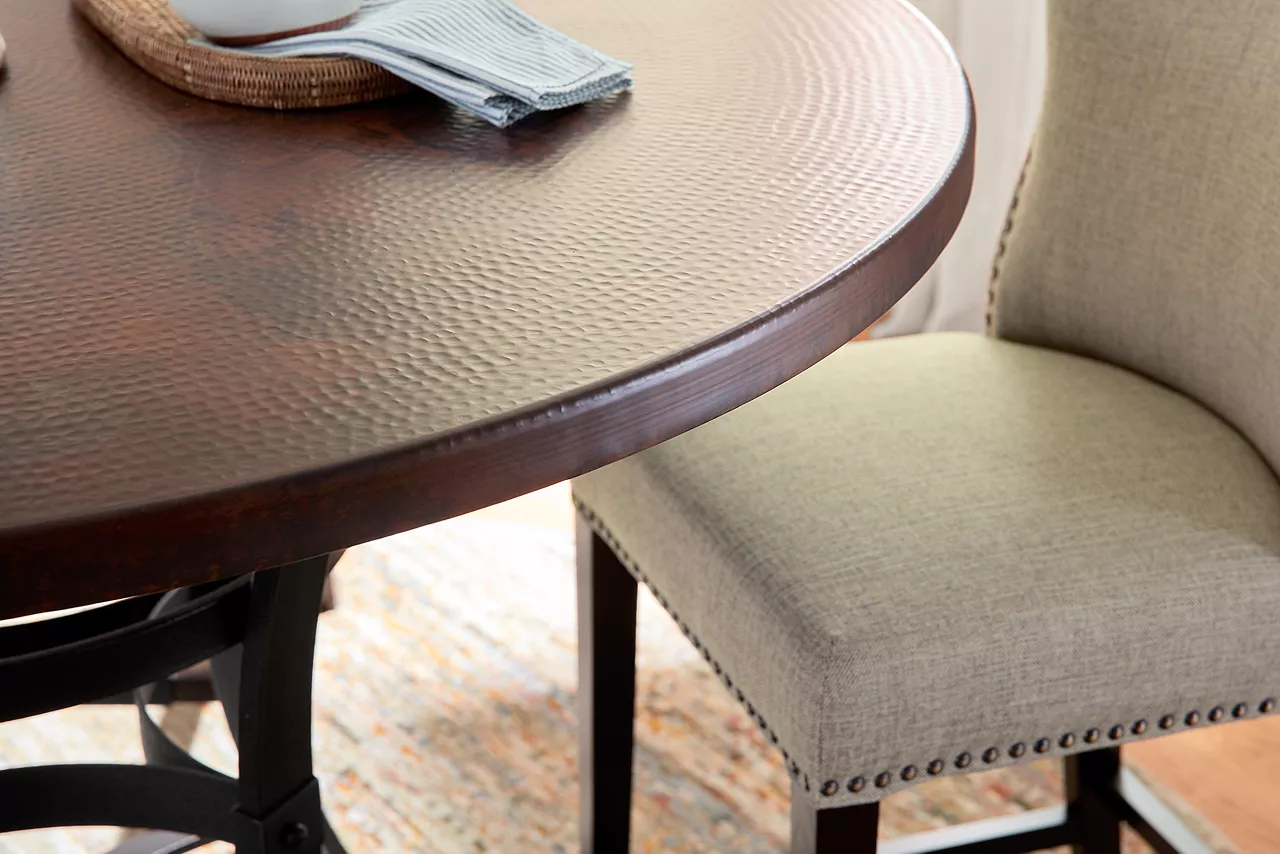 Closeup of the top of the Copper Canyon Counter-Height Table in Copper and Owen Counter-Height Stool in Linen in a room scene.