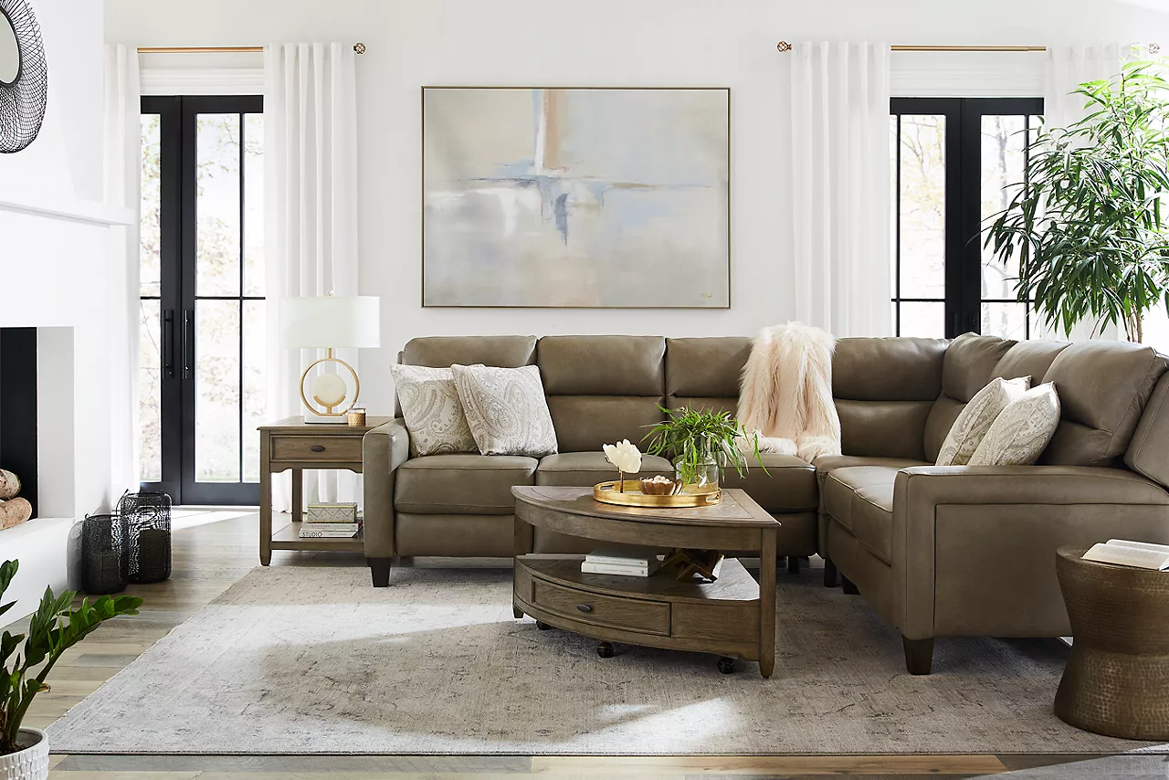 A leather Ava reclining Sectional and an Anniston Wedge Coffee Table and End Table in room scene.