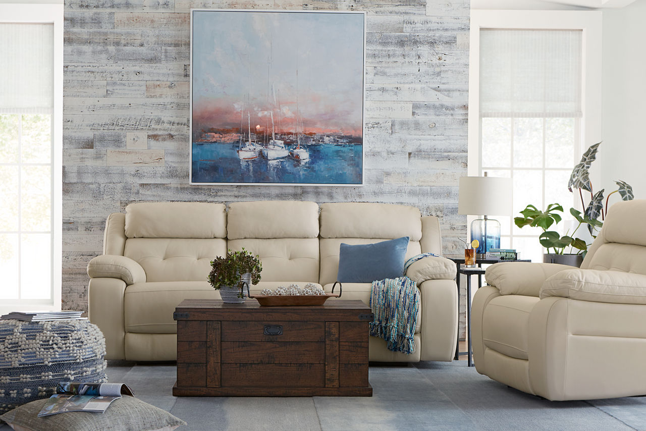 Sterling Sofa and Recliner in Cream and a Scottsdale Coffee Table in Rustic Chestnut and a Rudra Pouf in a room scene.
