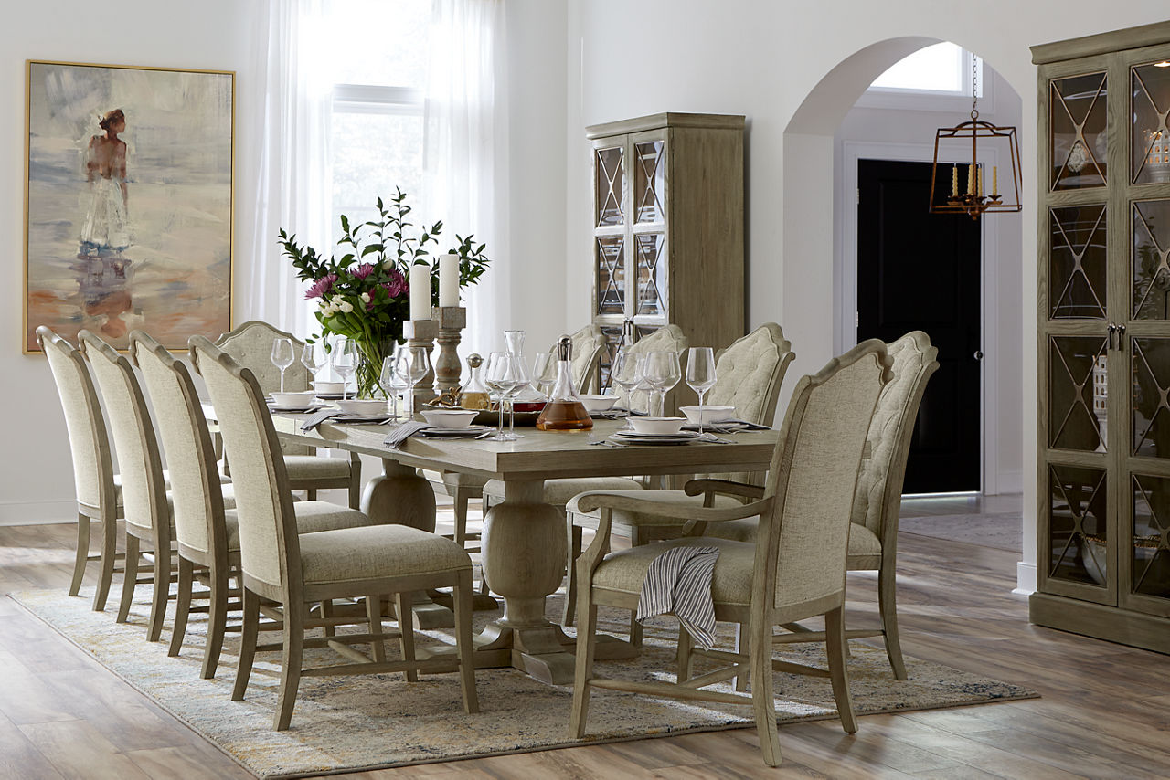 Candler Park Dining Table, Curio China Cabinets, Upholstered Dining Chairs, and Upholstered Armchairs in Burnished Grey in a room scene.