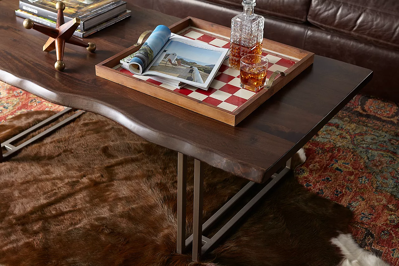 Coffee Table with drink and decanter in a checkboard tray and books and a metal Jack on top.