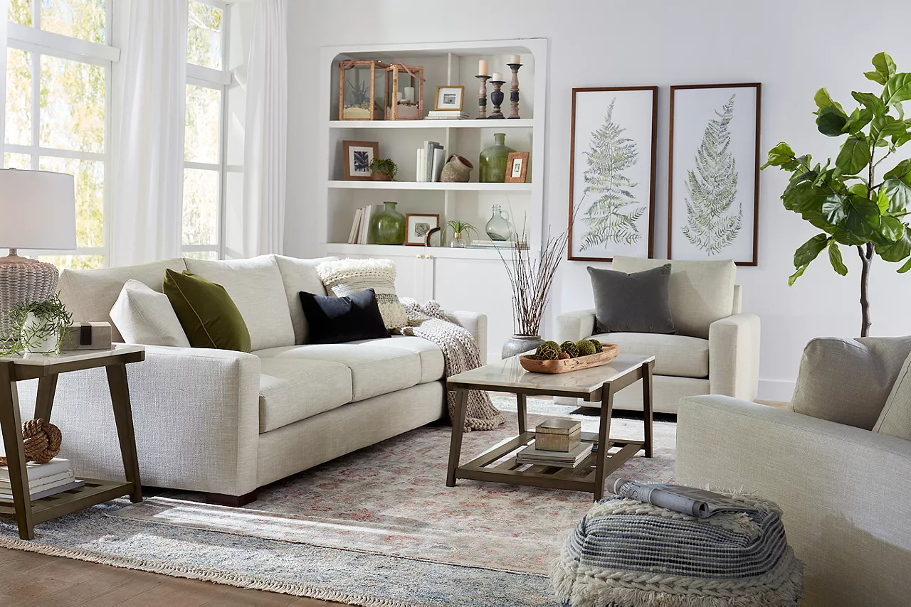 Destinations 3-Seat Sofa and Swivel Chairs in Convert Ivory and Emory Coffee Table and End Table in Weathered Sand in a room scene.