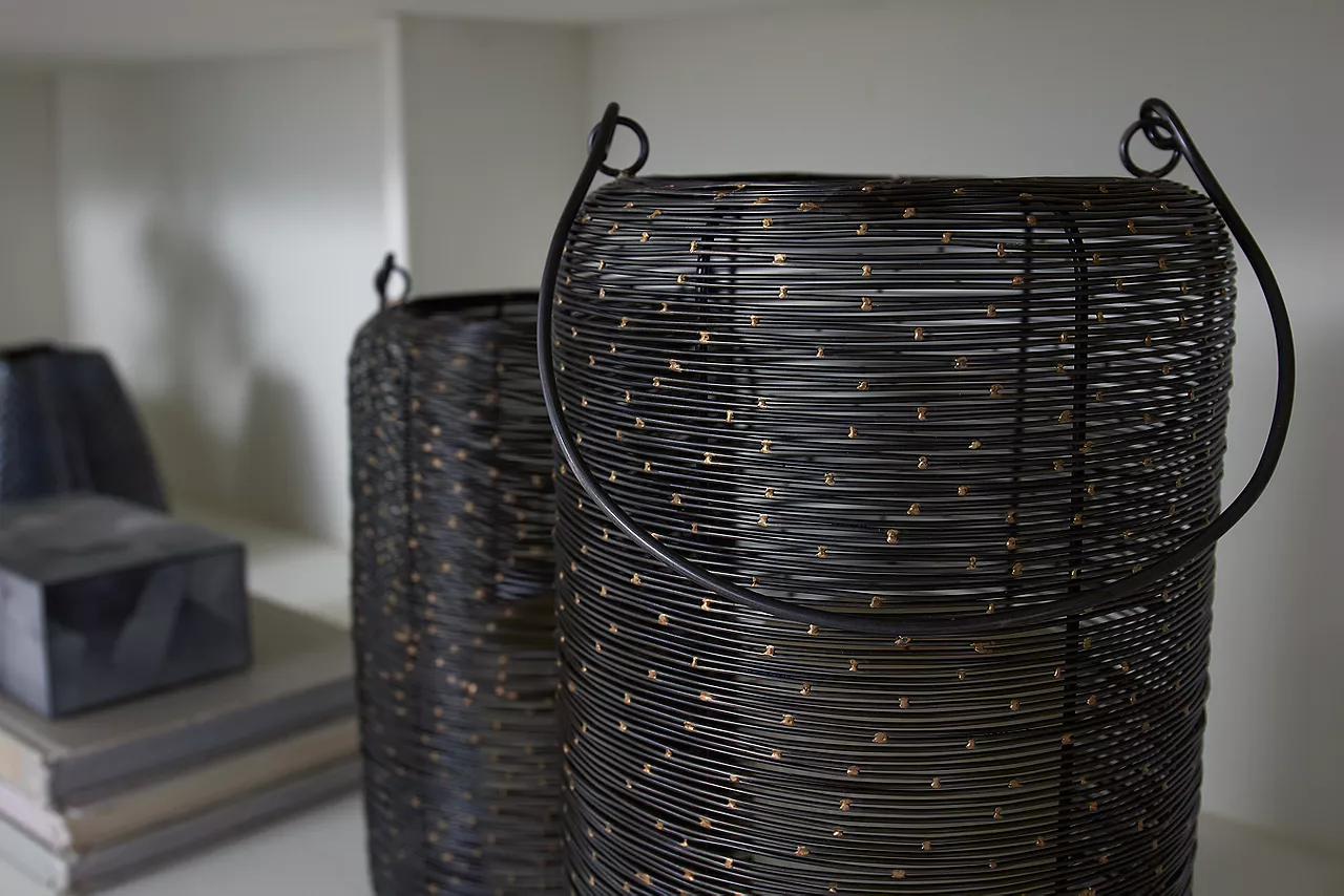 Closeup of a pair of dark brown woven baskets on a shelf in a room scene.