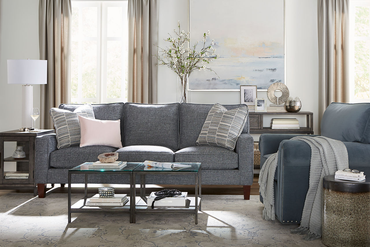 Katherine Sofa in Chelsea Graphite and Swivel Chair in Toscana Slate with two Keaton short bunching tables, a chairside table, and a sofa table in a room scene.