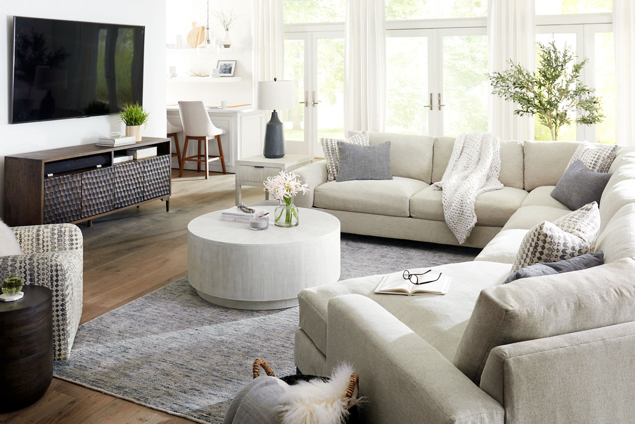 Harmony Sectional in Merit Dove, Harmony Swivel Chair in Hunky Dory Zinc, Knox Entertainment Console in Teak Grey, and Ginny Coffee Table in White Washed in a room scene.
