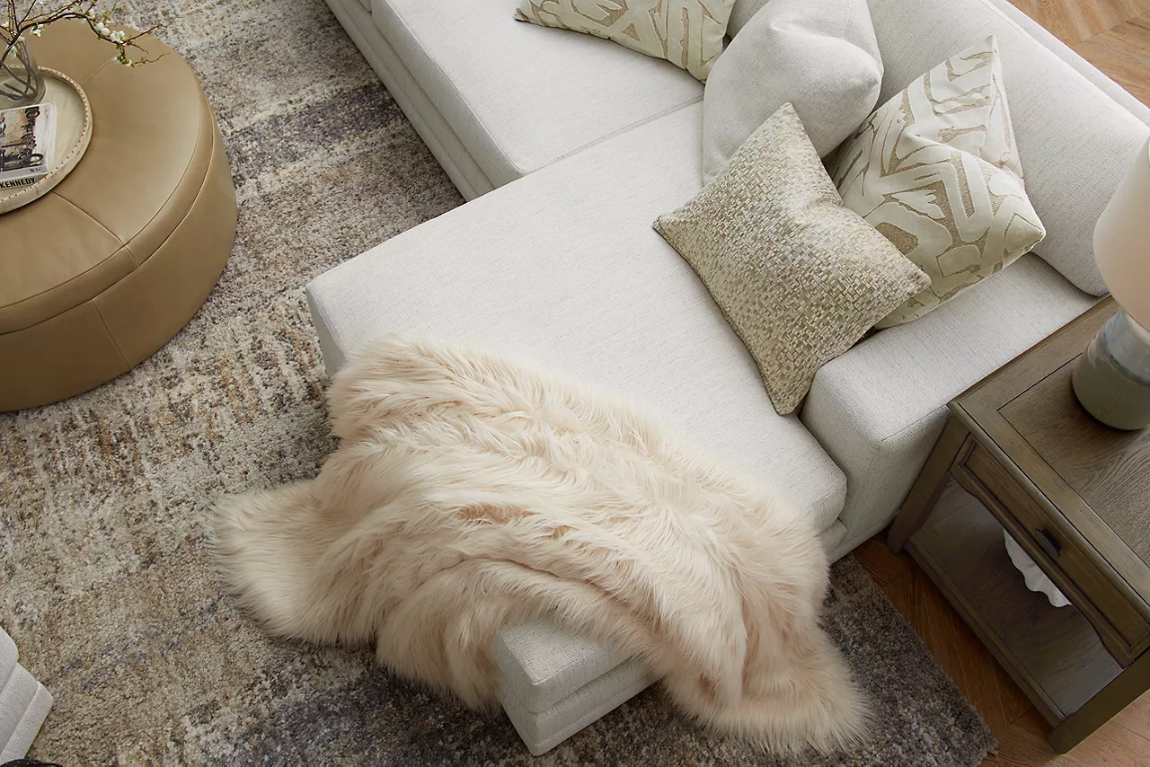 Overhead view of an Audrey sectional and storage ottoman and Anniston end table in a room scene.