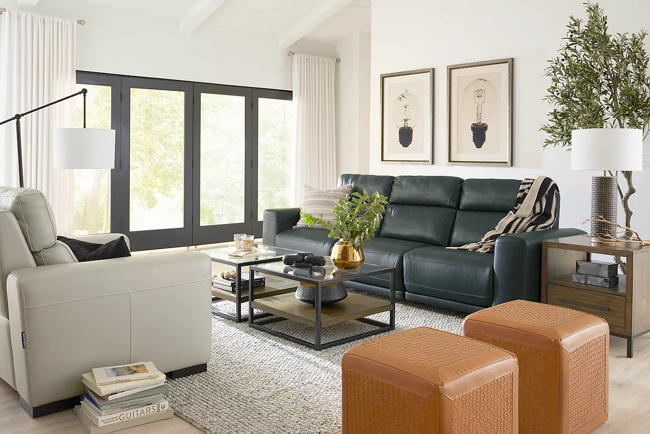  Genoa recliner in Smoke, Sofa in Slate and two archer square coffee and one end table and two Cash poufs, and an Indie table lamp in a room scene.