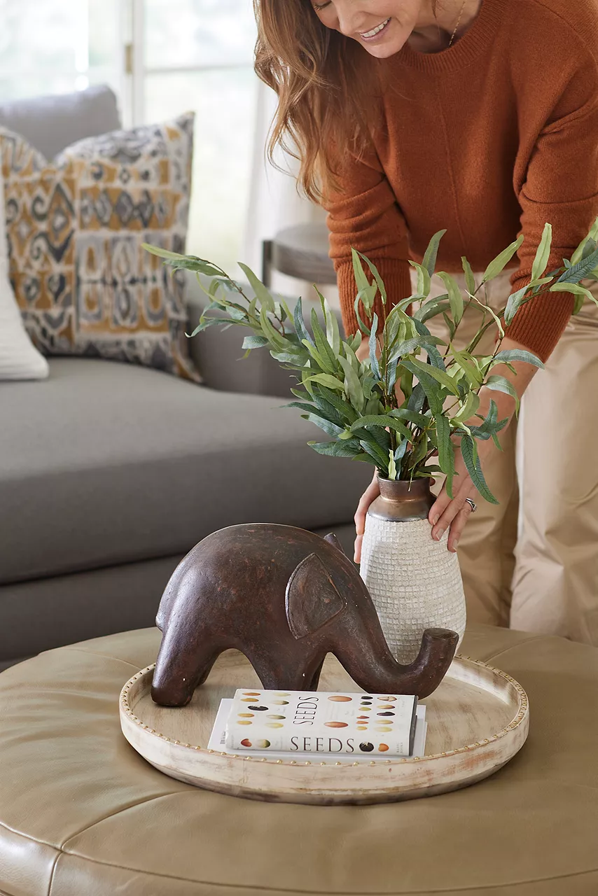 Woman placing plant on leather Audrey ottoman