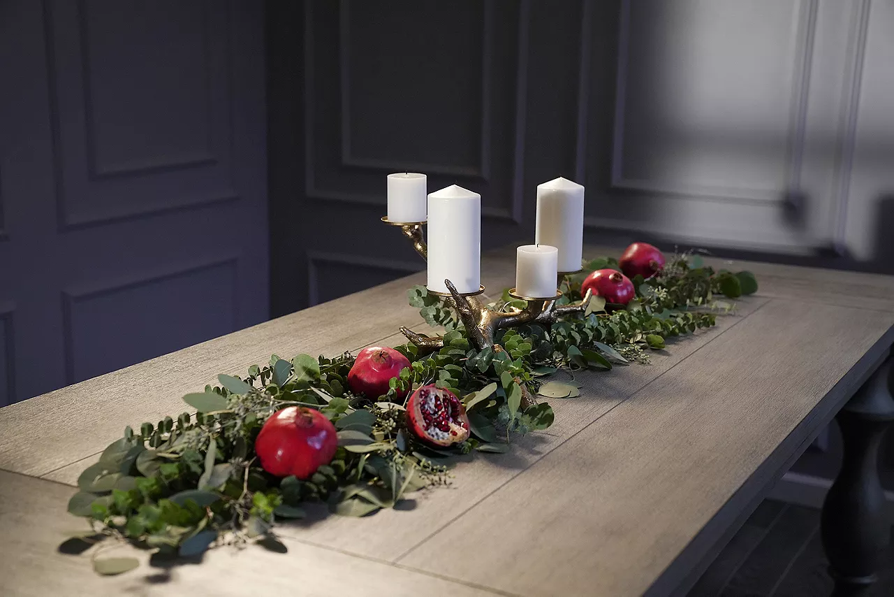 Image of table arrangement featuring candles and greenery