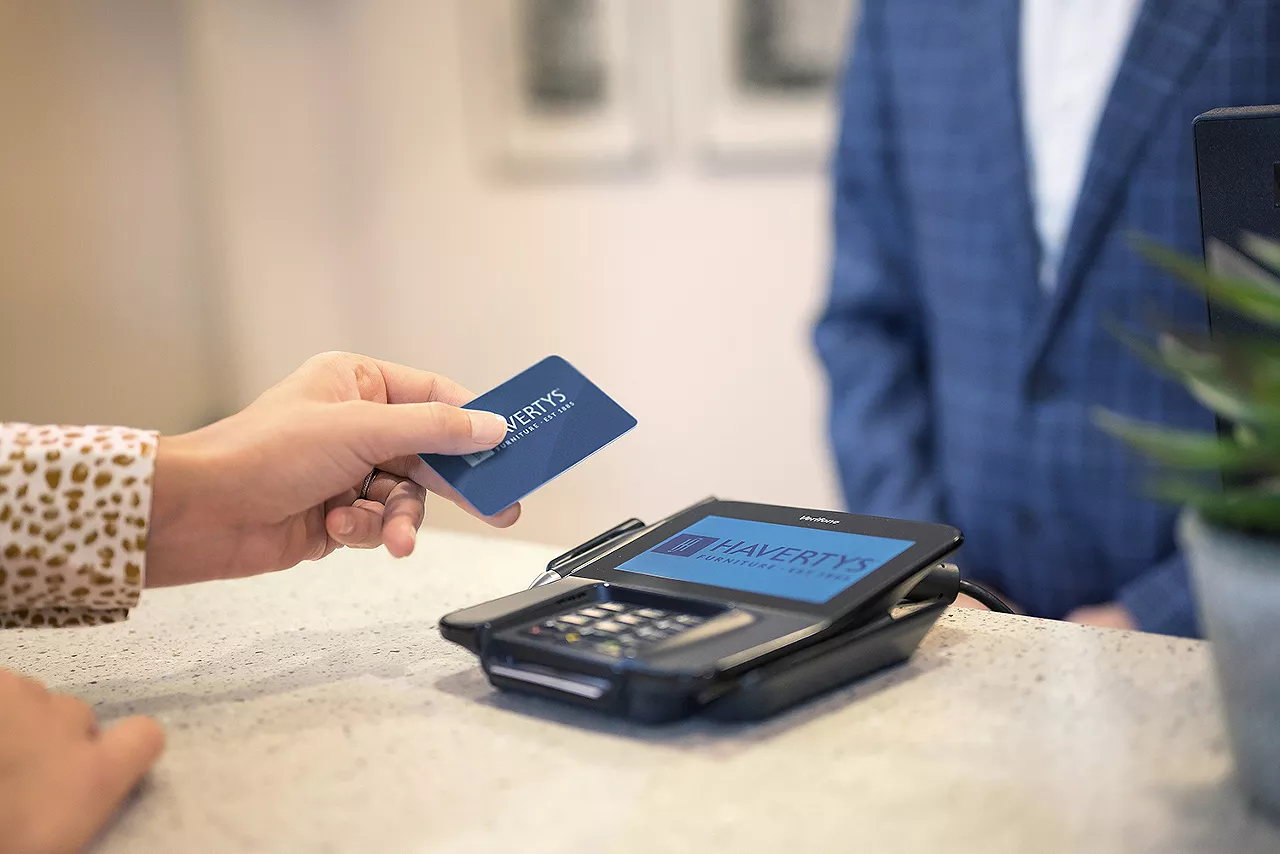 Image of a woman's hand holding a Havertys credit card about to make a furniture purchase