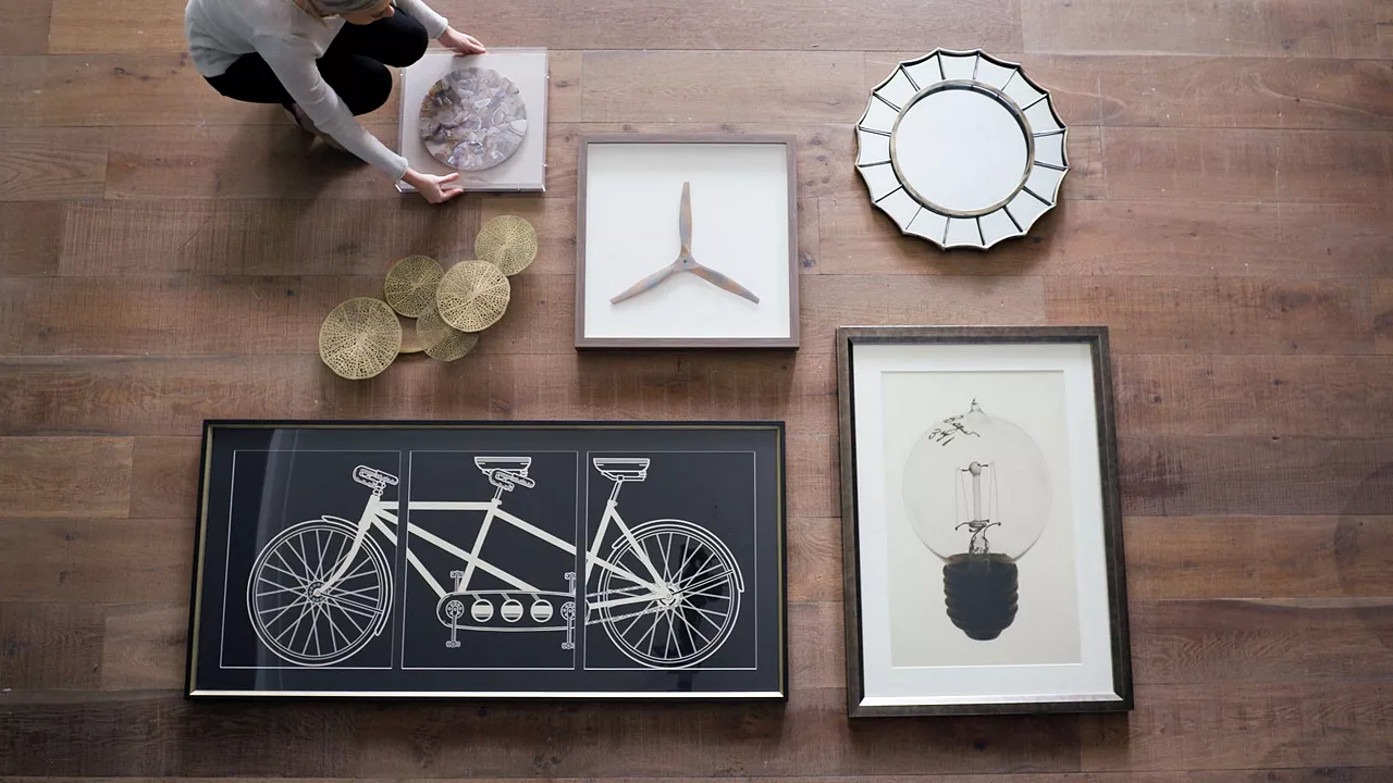 Image of woman planning out her wall art arrangement on the floor