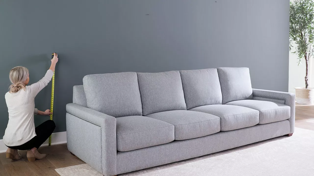 Woman taking measurements next to her sofa